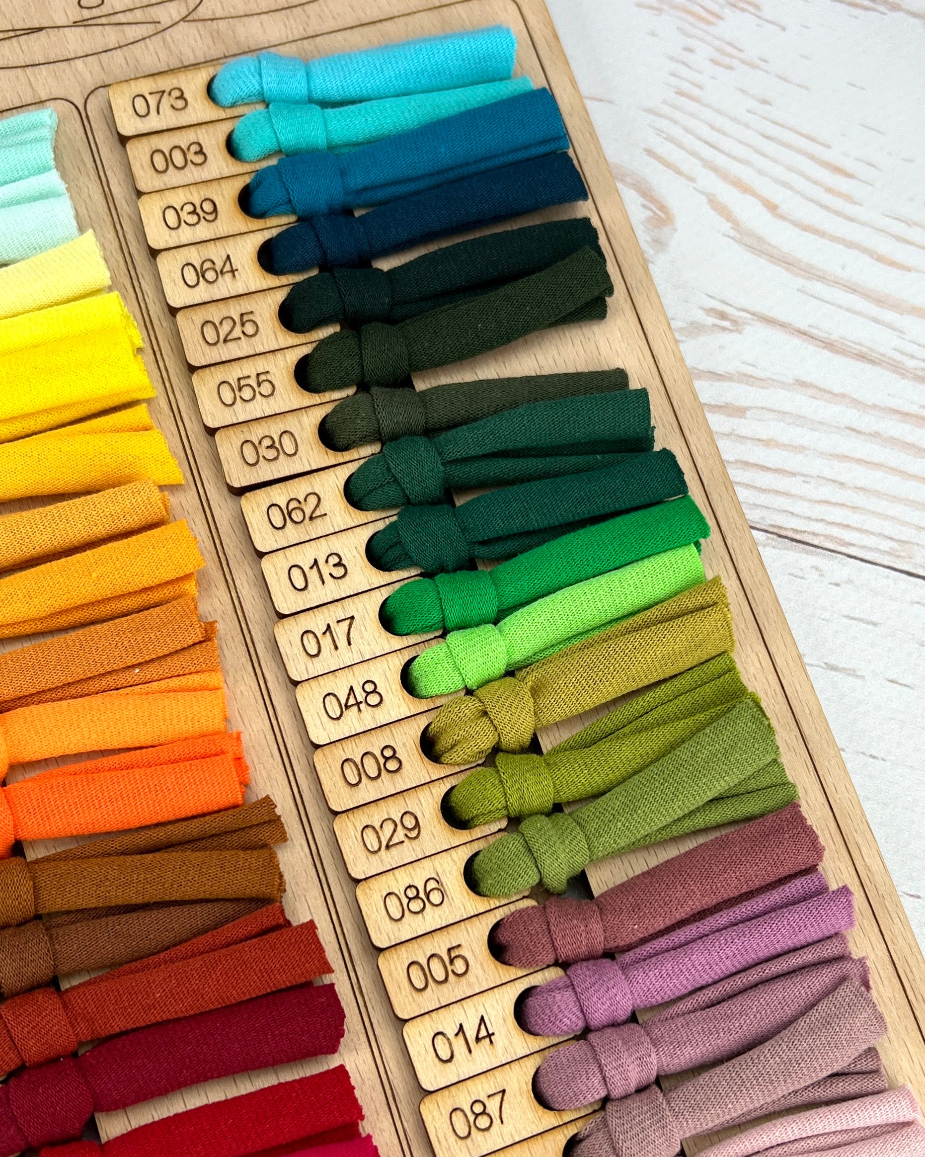 Color swatch chart with various colored bands on a wooden board
