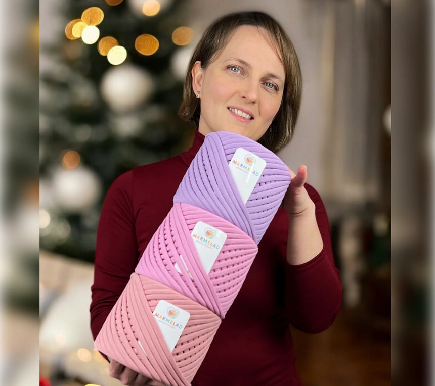Woman holding three skeins of yarn with a blurred background